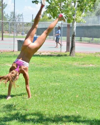 Cute gymnast does naked backflips by the tennis court #70972910